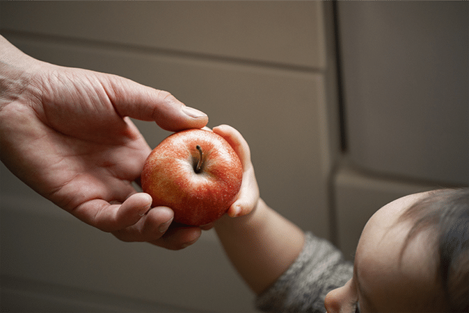 Persona handing apple to child